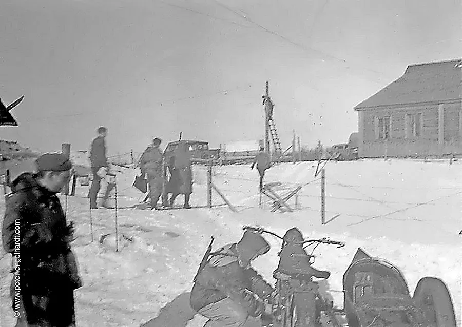 Februar 1944 vor dem Regimentsquartier steht ein Posten und ein Kradmelder Soldaten gehen mit Papieren durch den Schnee.