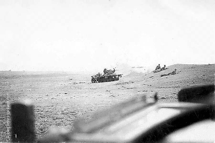 Sonder Kraftfahrzeug 10 feuert neben liegenden Soldaten mit dem 2cm Geschütz aus einer Bodenwelle, undatiert 1942 oder 1943.